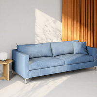 Light blue sofa with a textured pattern, paired with an orange curtain for a vibrant contrast in a modern interior.