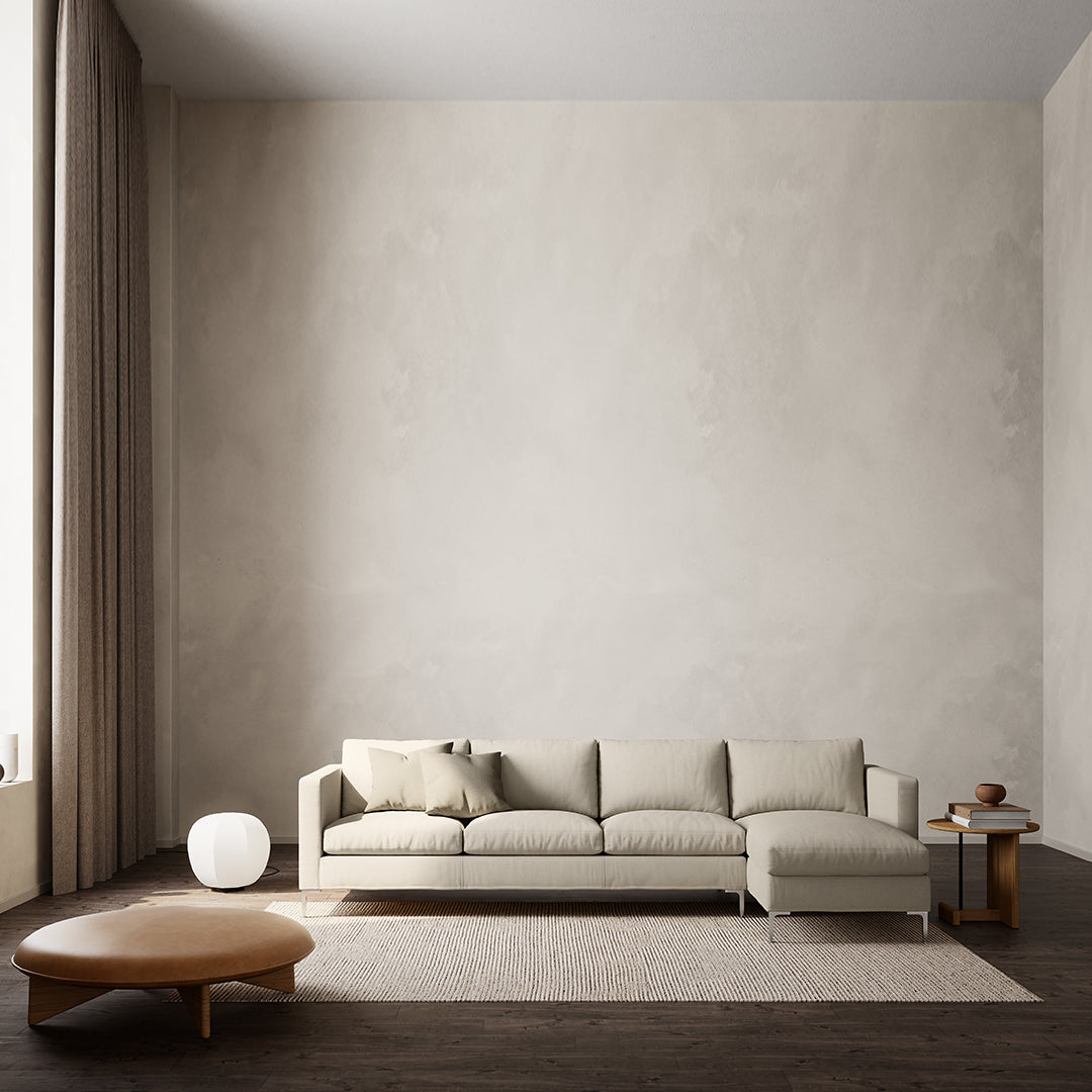 Neutral beige sectional sofa on a warm wood floor, accompanied by a round coffee table and minimalist decor.
