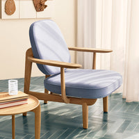 Light blue striped fabric armchair with natural wood frame, set against a soft beige backdrop. Stylish and modern design.