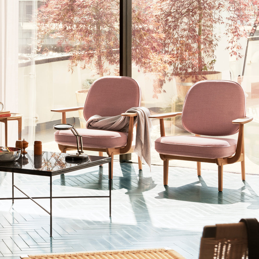 Pair of soft pink chairs with wooden frames, bright blue floor, and natural light enhancing the serene decor.