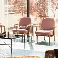 Pair of soft pink chairs with wooden frames, bright blue floor, and natural light enhancing the serene decor.