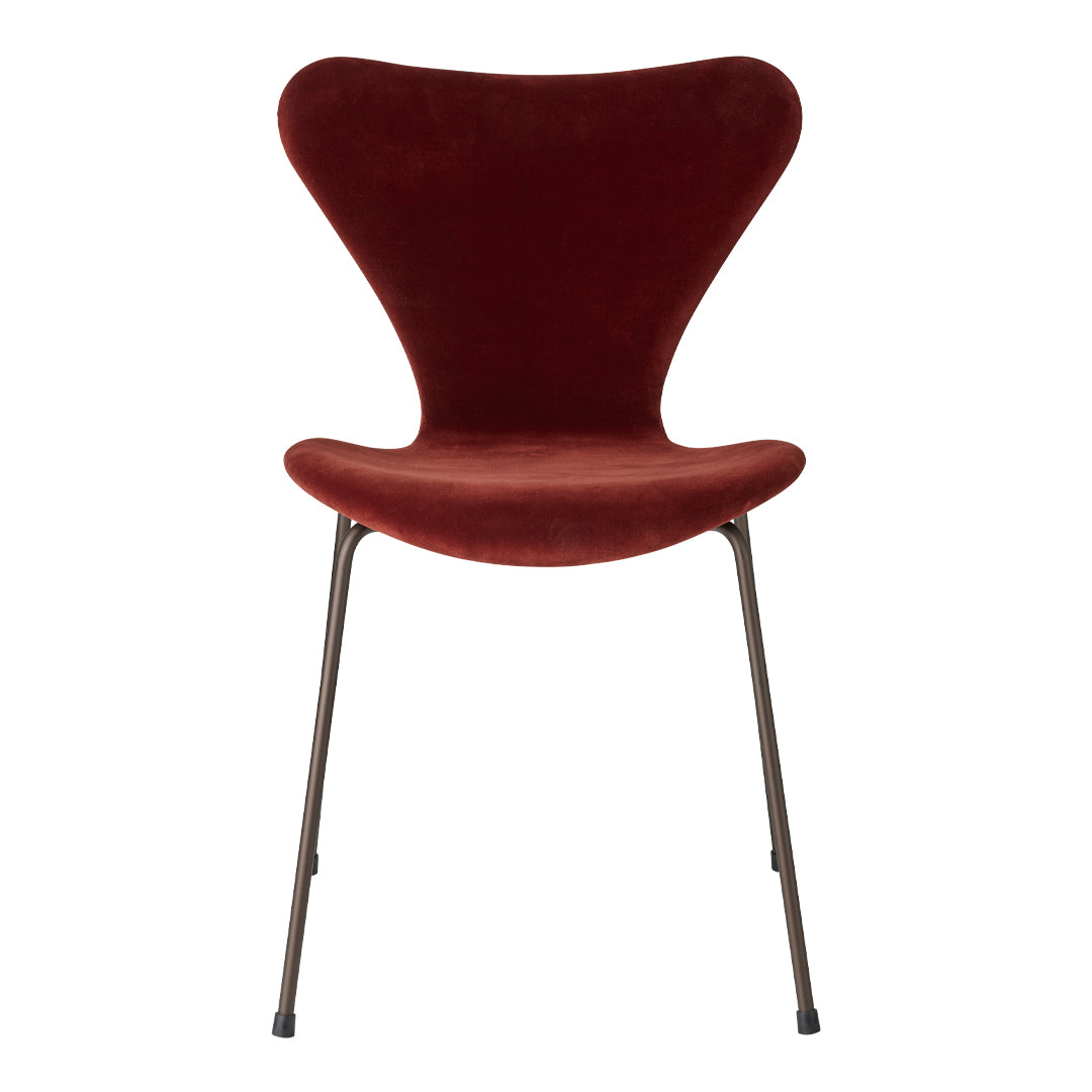 Curved velvet chair in rich burgundy with sleek metal legs, perfect for modern decor.