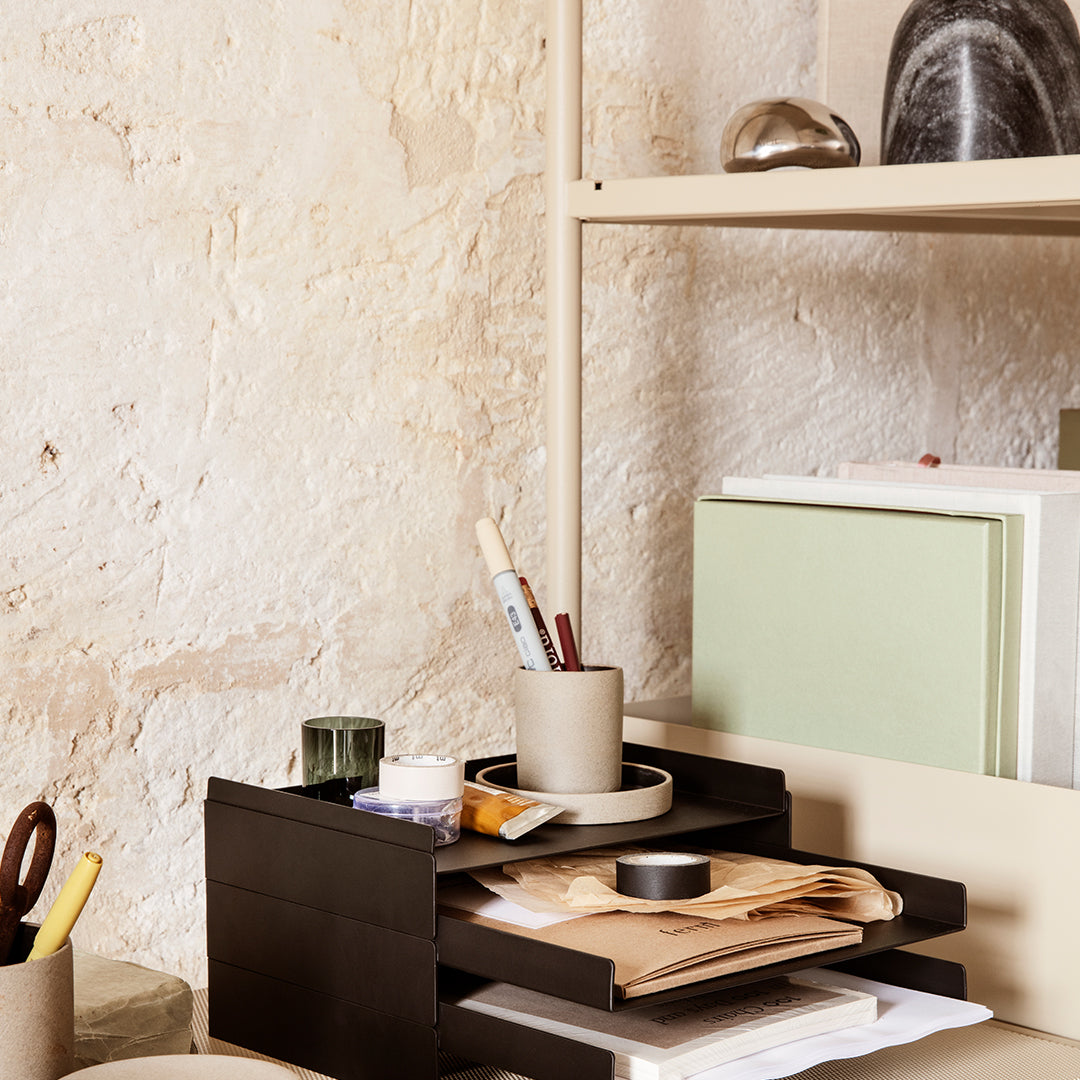 Black storage organizer with green accents, neutral backgrounds, and minimalistic patterns on desk items.