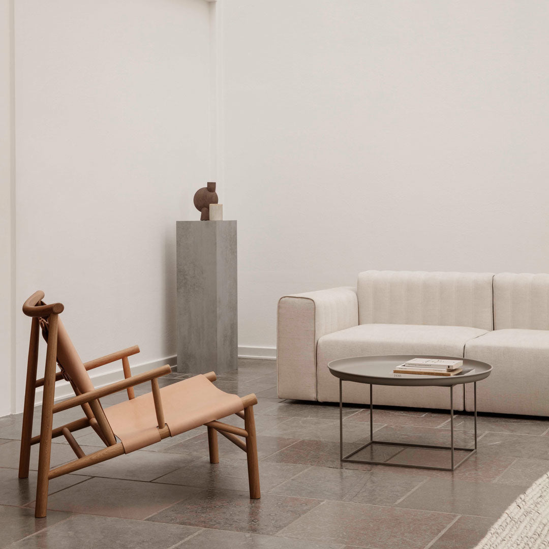 Neutral beige and soft white tones on a modern sofa and chair, complemented by a minimalist gray accent table.