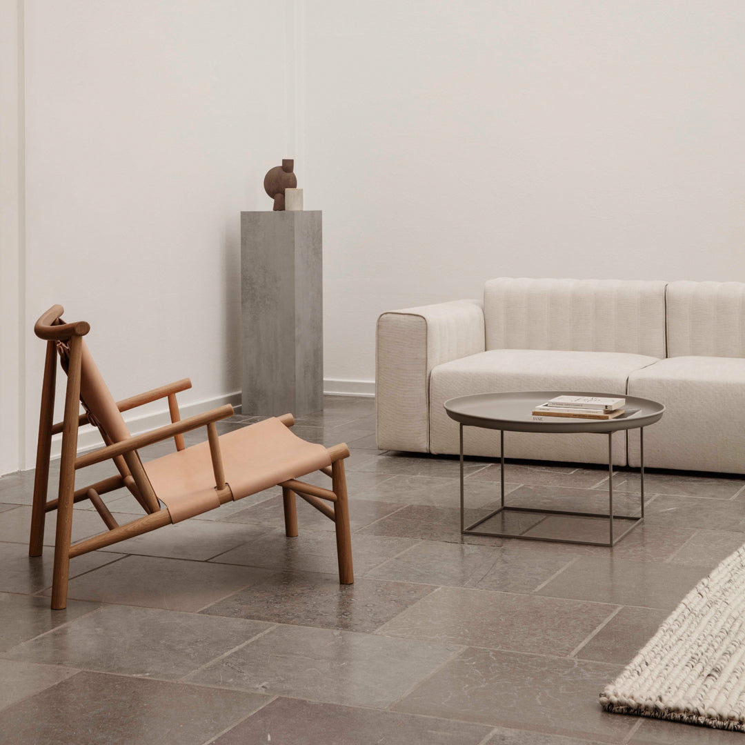 Natural wood tones, beige upholstery, and minimalist gray patterns create a serene, modern living space.