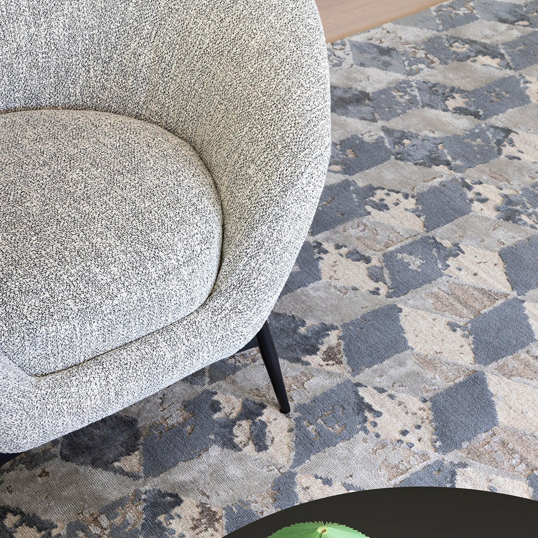 Light gray textured chair on a geometric blue and gray patterned rug, featuring soft neutral tones.