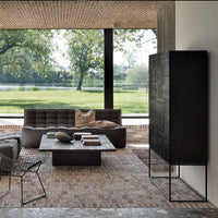 Modern living room featuring a black cabinet, gray furniture, and earthy tones, with a natural pattern of greenery outside.