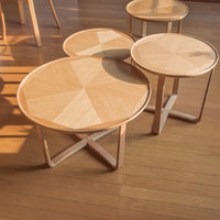 Natural wood round side tables featuring a geometric light oak pattern on the top and minimalist white legs.