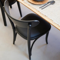 Black curved dining chair with sleek design, featuring smooth surfaces and minimalistic patterns.