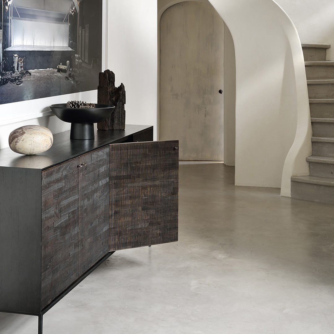 "Textured black cabinet with horizontal grooves, complemented by neutral tones and smooth concrete flooring."