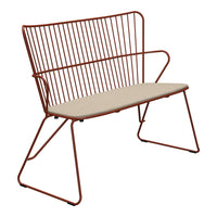 Rust-colored metal bench with a minimalist design and cream-colored cushion for added comfort.