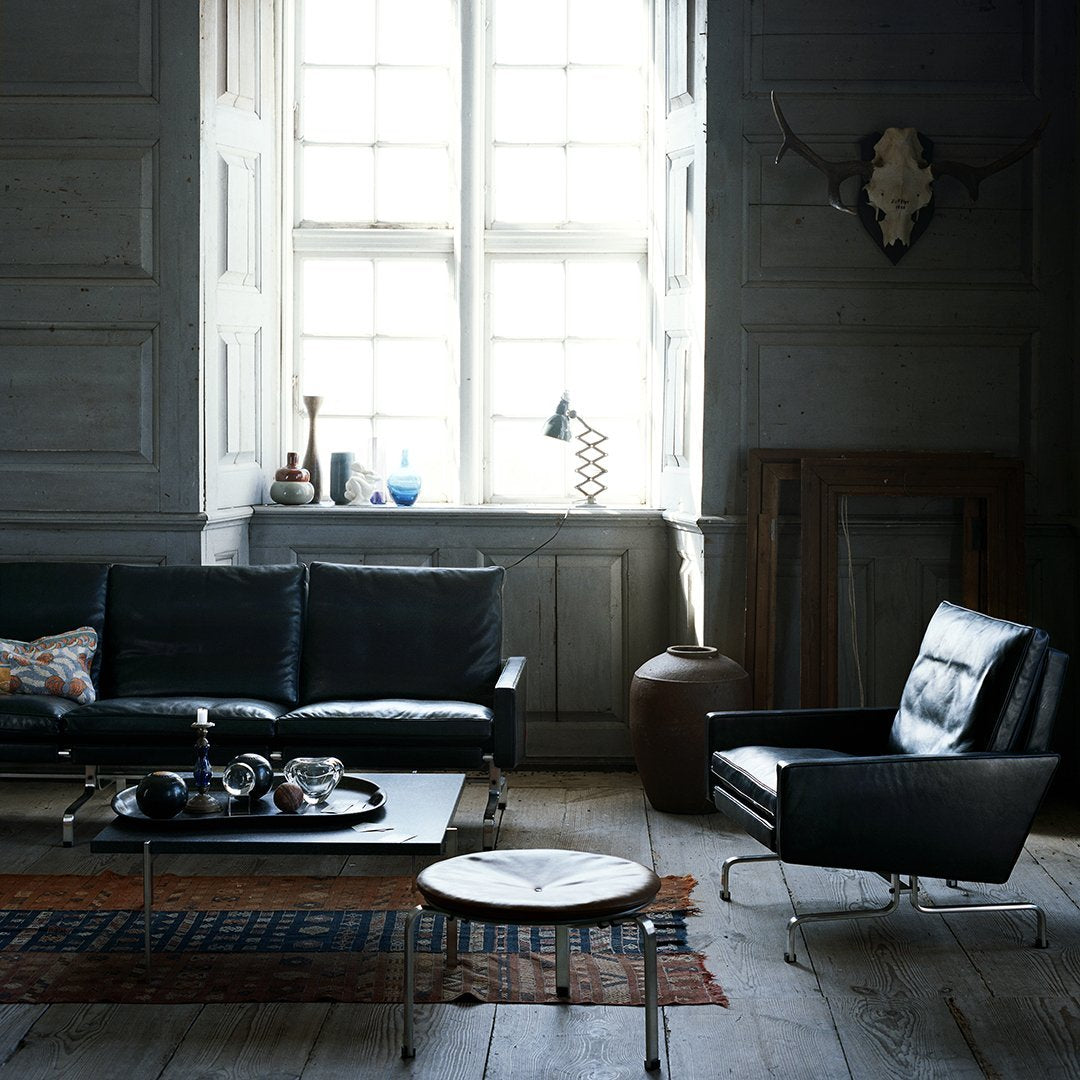 "Modern black leather sofa and armchair, featuring a textured area rug in warm tones against a soft gray backdrop."