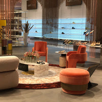Stylish interior featuring coral chairs, marble table, and colorful shoes against a vibrant, patterned backdrop.