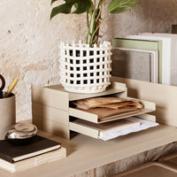 "Neutral-toned desk organizer with a white woven pot, featuring soft beige and green accents, set against a rustic backdrop."