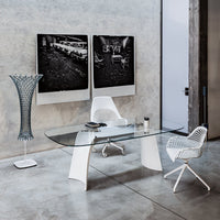 Modern glass office desk with sleek white chairs and a unique patterned floor lamp, set against a gray wall.