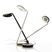 Modern desk lamps in black and white with sleek, minimalist designs and circular light patterns.
