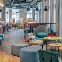 Cozy lounge with blue, gray, and yellow seating, featuring modern designs and varied textures in a stylish setting.