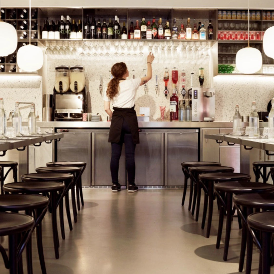 "Modern bar with sleek white countertop, black chairs, and stylish lighting, showcasing a minimalist color palette."