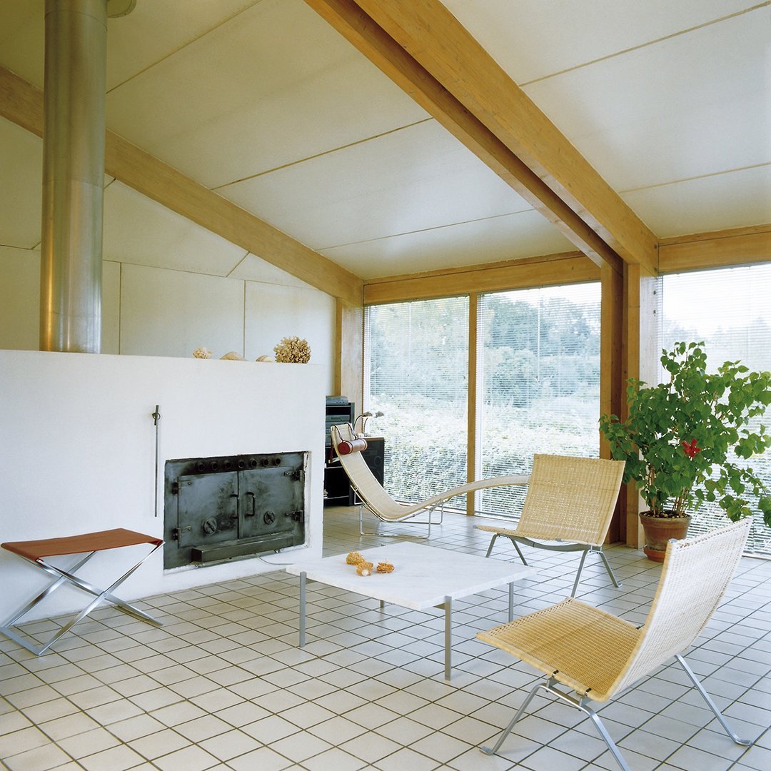 Modern indoor seating featuring natural wood tones, beige cushions, and a sleek white fireplace against tiled flooring.