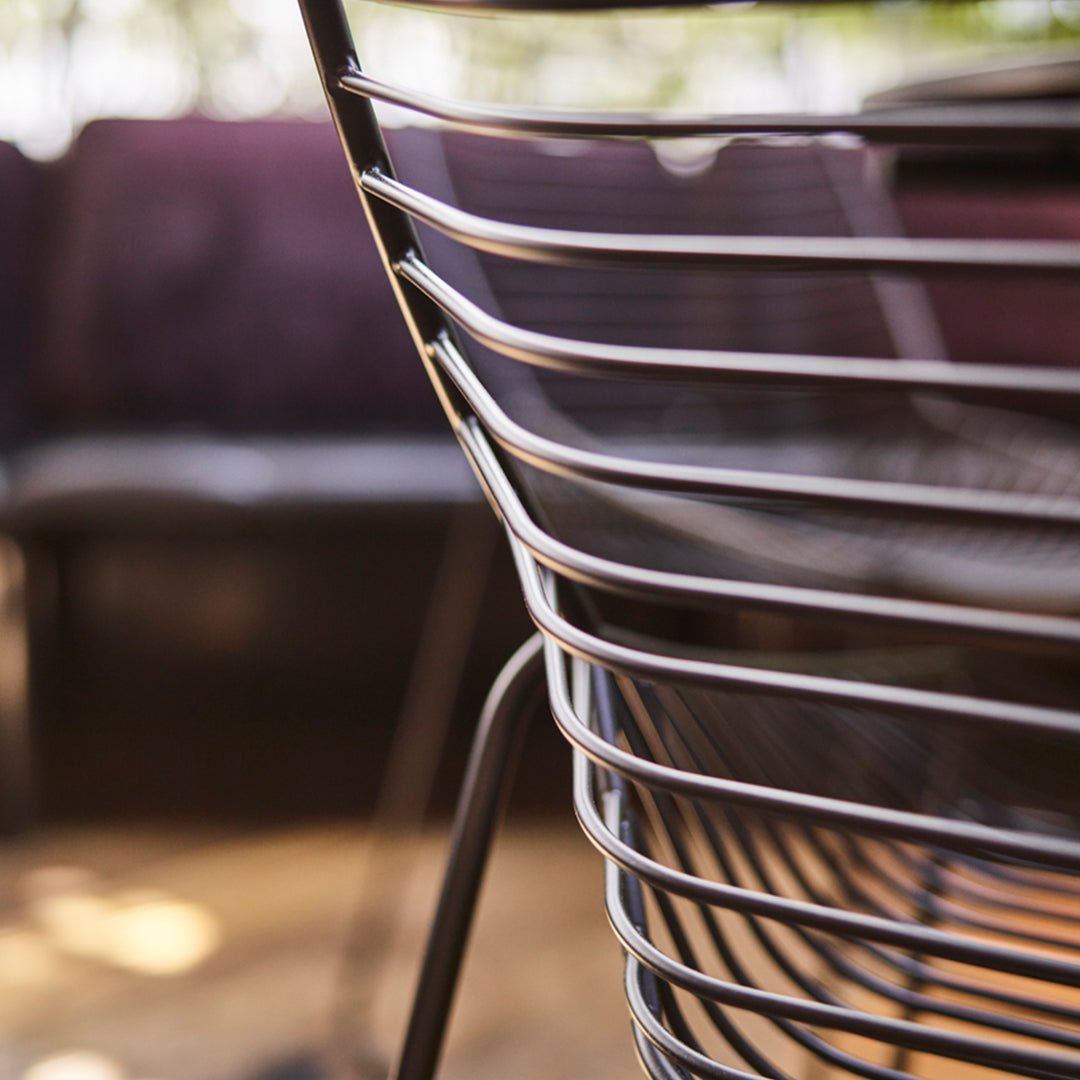 Silver metal chair with curved, sleek lines and a minimalist design against a blurred purple backdrop.