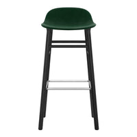 Green velvet bar stool with a sleek black frame and chrome footrest, featuring a smooth, modern design.