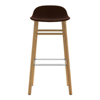 Brown upholstered bar stool with natural wood legs and a chrome footrest, featuring a sleek, minimalist design.