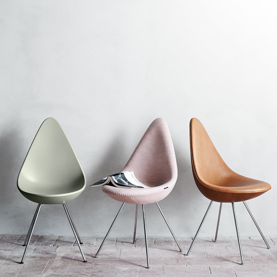 Three modern chairs in muted green, soft pink, and warm brown, featuring sleek metal legs and a minimalist design.