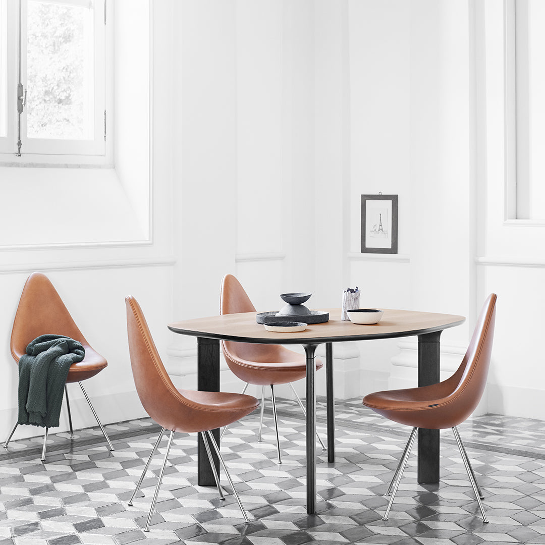 "Modern dining set featuring tan chairs against a white backdrop and geometric black-and-white tile floor."