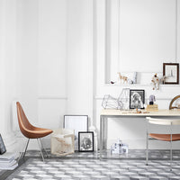 Modern office with a white color scheme, copper chair, and geometric gray patterned flooring.