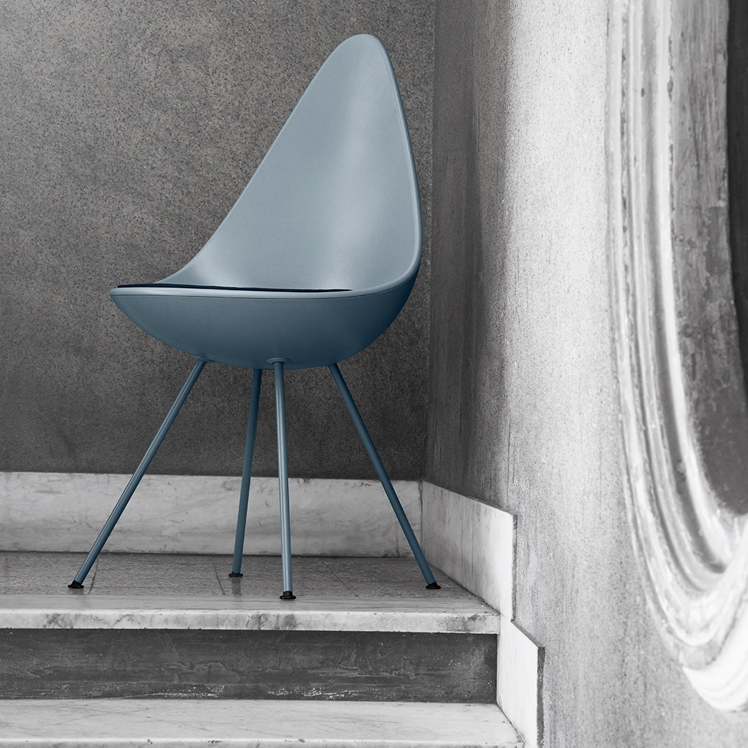 Modern blue teardrop chair with sleek lines, paired with gray and marble accents for a minimalist aesthetic.
