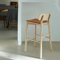 Light wood stool with a warm brown seat, featuring a minimalistic design and smooth, clean lines. Ideal for modern decor.