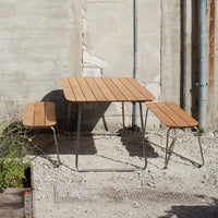 Light brown wooden patio table and benches with a sleek, modern design against a textured gray background.