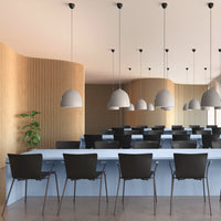 Modern interior with wooden paneling, gray pendant lights, and black chairs against a light blue counter.