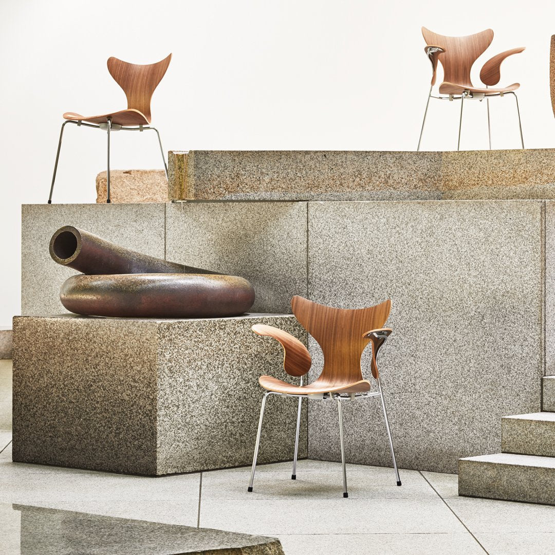 Warm wood tones on stylish chair, set against textured gray stone and smooth shapes, creating a modern aesthetic.