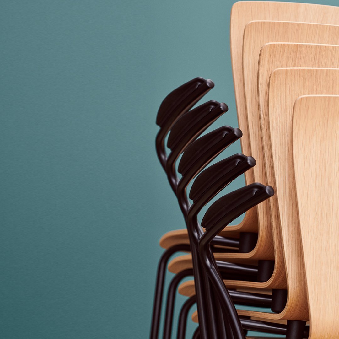 Stacked chairs with light wood seats and sleek black metal frames against a teal background.