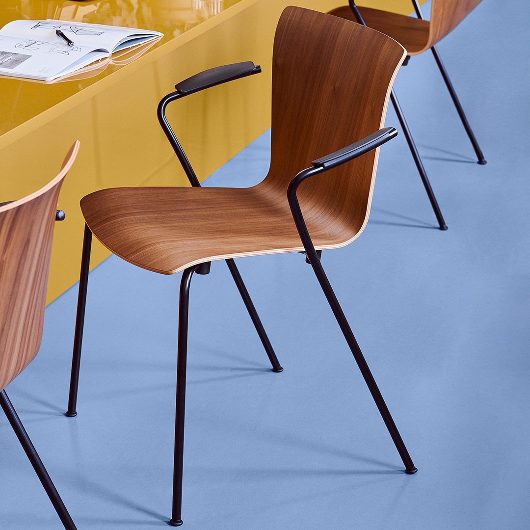 Wooden chair with a curved back, complemented by black metal legs on a light blue floor and yellow table surface.