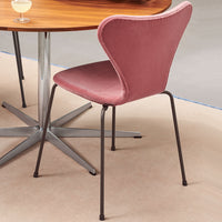 Pink upholstered dining chair with a sleek black metal base, featuring a modern curved design. Ideal for stylish interiors.