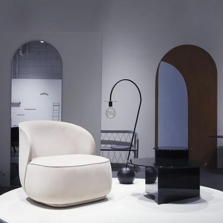 Cream-colored accent chair beside a sleek black table, set against minimalist gray and warm wooden tones.
