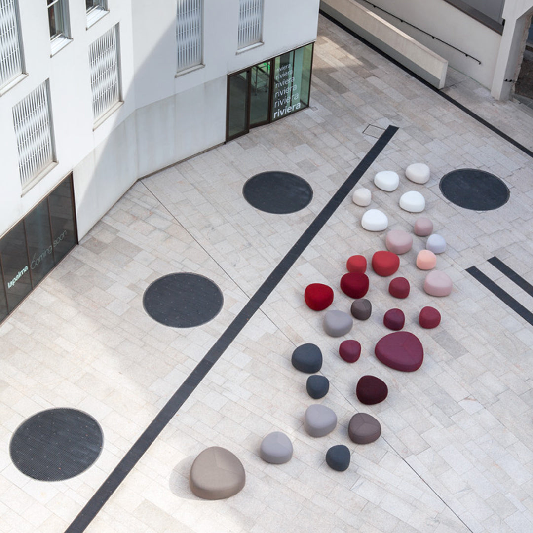 Colorful circular cushions in shades of red, pink, gray, and black arranged on a light stone floor.