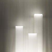 Modern white geometric light sculptures in varying heights, set against a sleek gray backdrop.