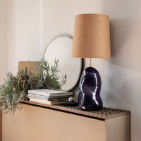 Vibrant purple ceramic lamp with a textured finish and a neutral burlap shade, styled with greenery and a mirror.