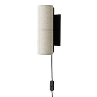 Cream cylindrical wall light with a textured surface and black metal mount, featuring a sleek, modern design.