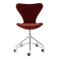 Red velvet upholstered chair with a sleek chrome base and wheels, featuring a modern, curvy design.