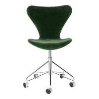 Green velvet swivel chair with a sleek chrome base and smooth lines, perfect for modern decor.