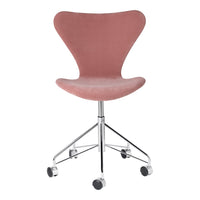 Pink velvet chair with a sleek curved design, featuring a chrome base and rolling wheels for easy mobility.