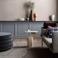 Modern living room featuring a gray wall, neutral tones, plush gray seating, and patterned throw pillows in burgundy and navy.