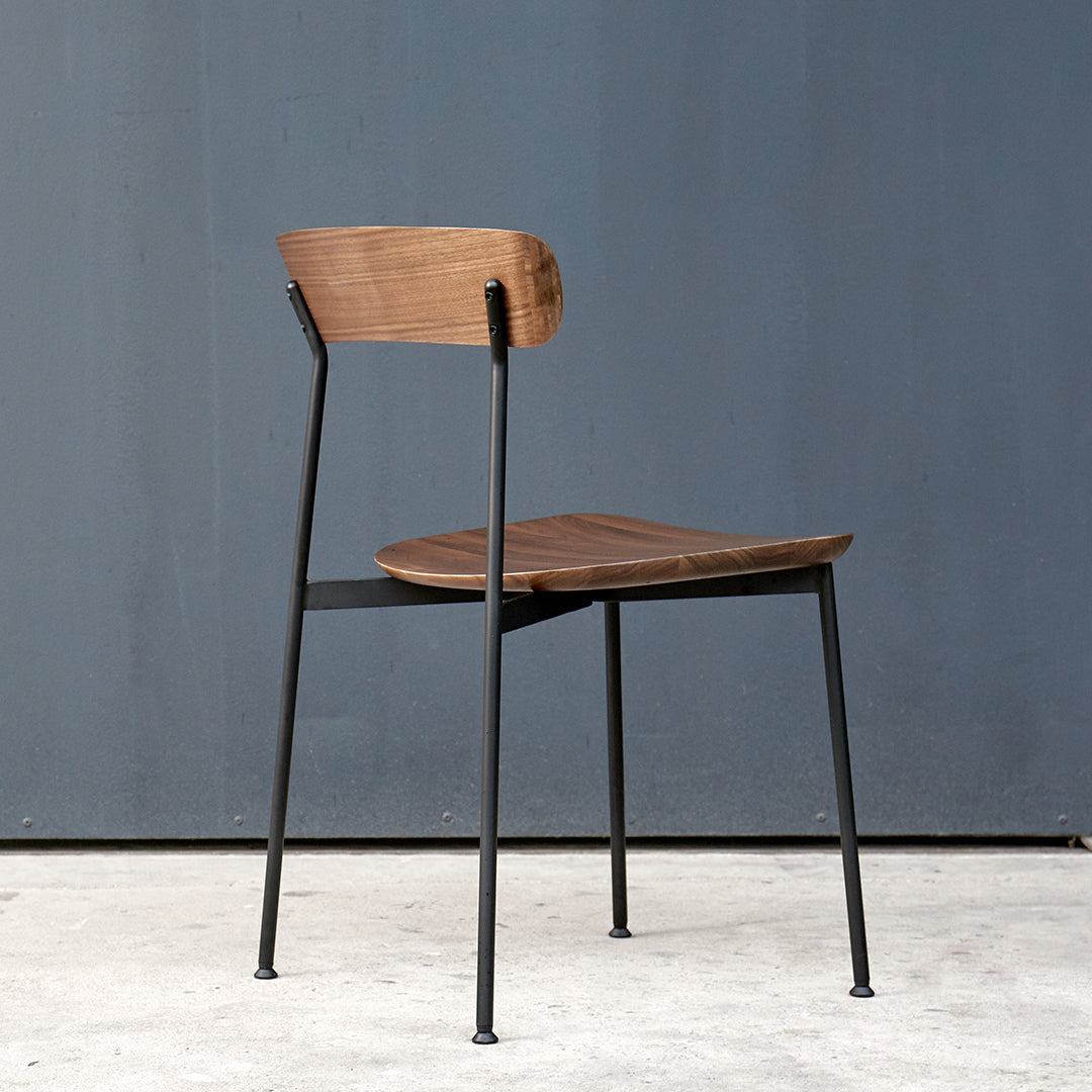 Wooden chair with a warm brown seat and backrest, contrasted by sleek black metal legs. Minimalist design.