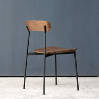 Wooden chair with a warm brown seat and backrest, contrasted by sleek black metal legs. Minimalist design.