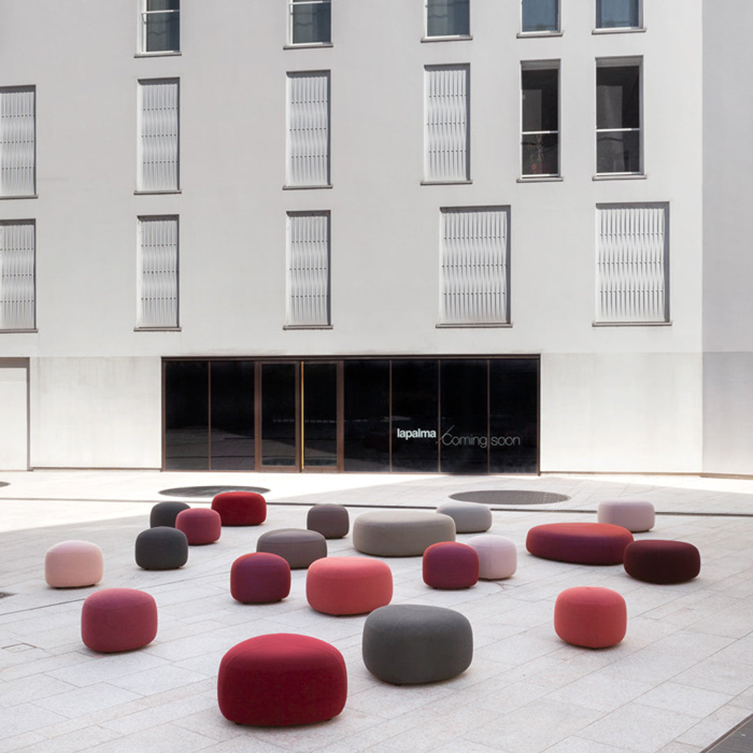 Colorful modern poufs in shades of pink, red, and gray on a sleek urban plaza. Perfect for stylish outdoor seating.