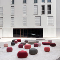 Colorful modern poufs in shades of pink, red, and gray on a sleek urban plaza. Perfect for stylish outdoor seating.